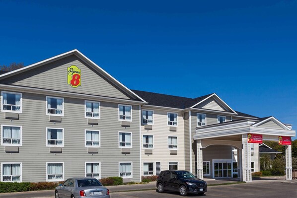 A Super 8 hotel with a two-story structure, multiple windows, and a covered entrance. - Super 8 by Wyndham Midland (Midland)