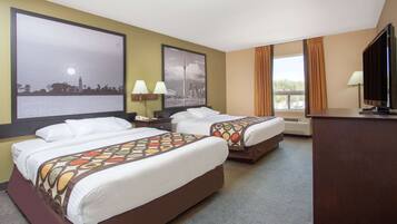 A hotel room with two beds, a desk, a television, and large windows.