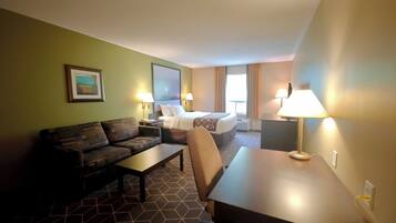 A hotel room with a sofa, a bed, a desk, and a lamp.