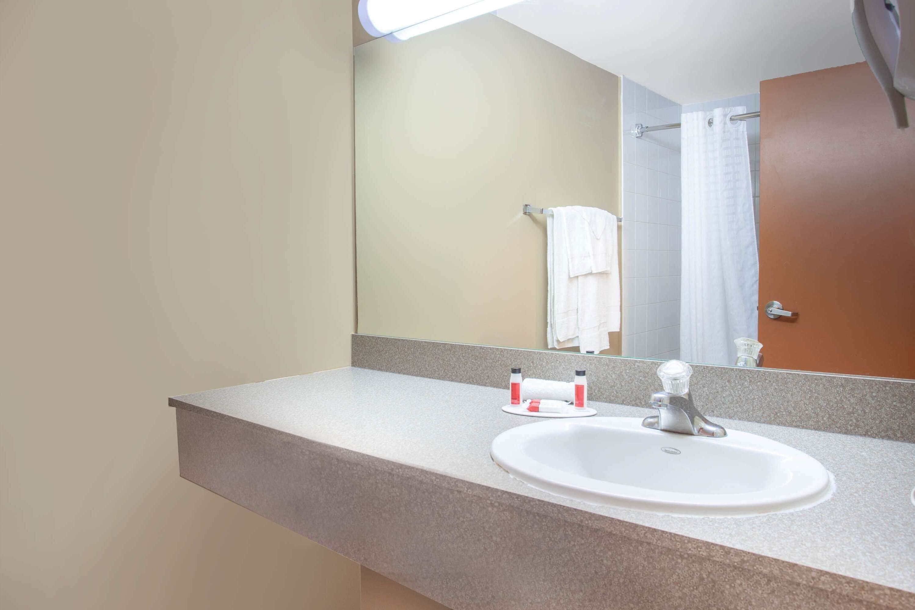 A bathroom with a sink, mirror, and towel rack.