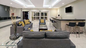 A modern living area with a sofa, chairs, a coffee table, and a decorative vase. - La Quinta Inn & Suites by Wyndham Mercedes Outlet Mall (Mercedes)
