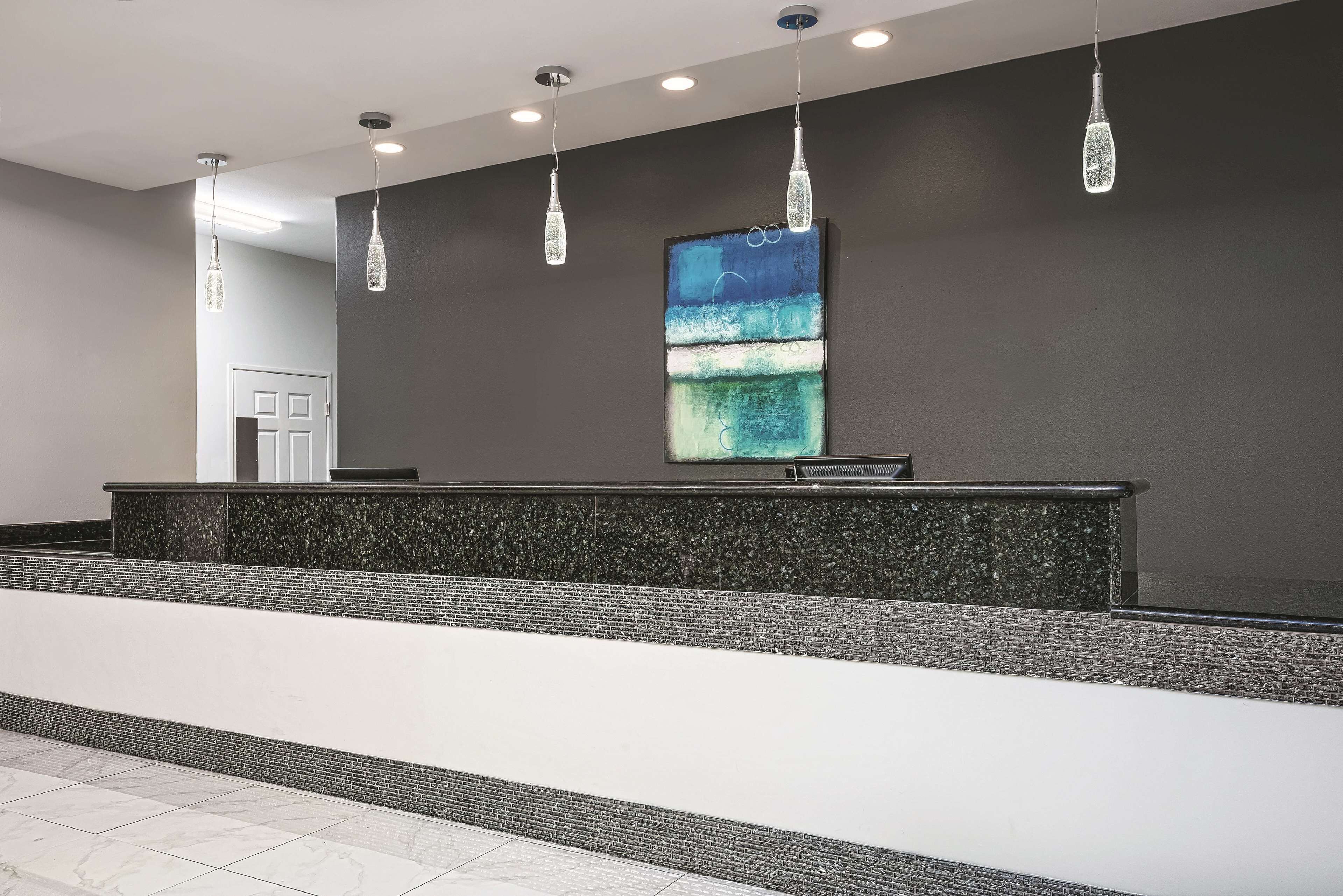 A reception area with a dark wall, a large abstract painting, and a reception desk.