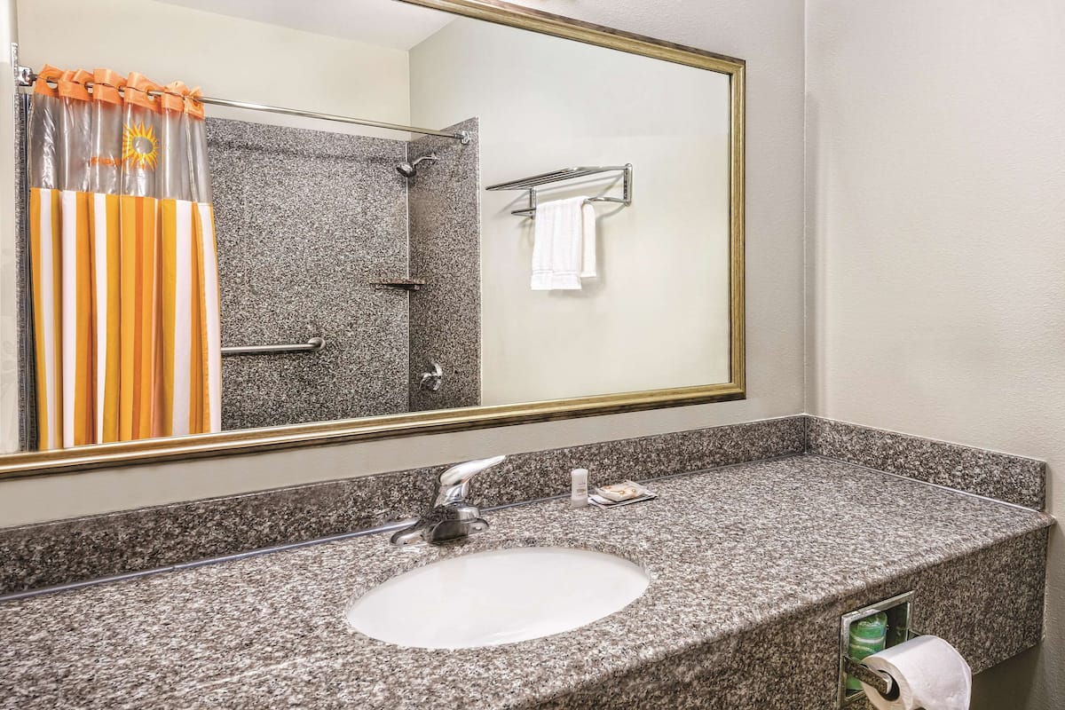 A bathroom with a granite countertop sink, a shower with a glass door, and a towel rack.