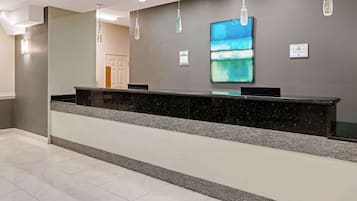 Un'area reception con un bancone in marmo, lampade a sospensione e un grande quadro astratto appeso al muro.
