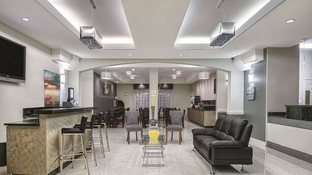 A modern hotel lobby with a bar area, seating, and a television. - La Quinta Inn & Suites by Wyndham Mercedes Outlet Mall (Mercedes)