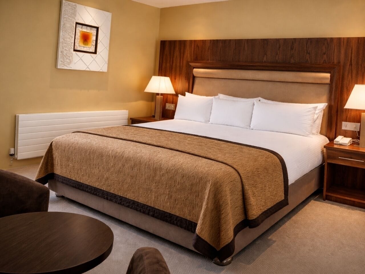 A hotel room with a large bed, two bedside tables, a chair, and a wall-mounted artwork.