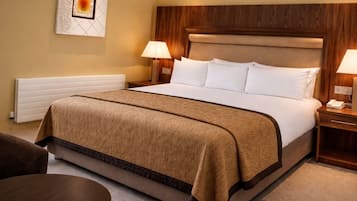 Une chambre d’hôtel avec un grand lit, deux tables de chevet, une chaise et une œuvre d’art accrochée au mur.