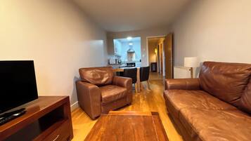A living room with a sofa, a chair, a TV stand, and a wooden coffee table.