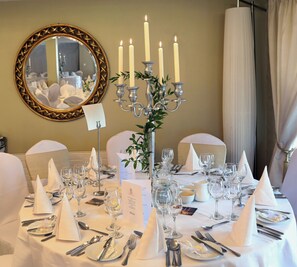 A formal dining table with white linens, silverware, and wine glasses, a candelabra with candles, and a mirror with a gold frame. - Annebrook House Hotel (Mullingar)