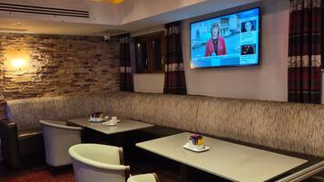 A restaurant with a stone wall, a TV screen, and a red carpeted floor.