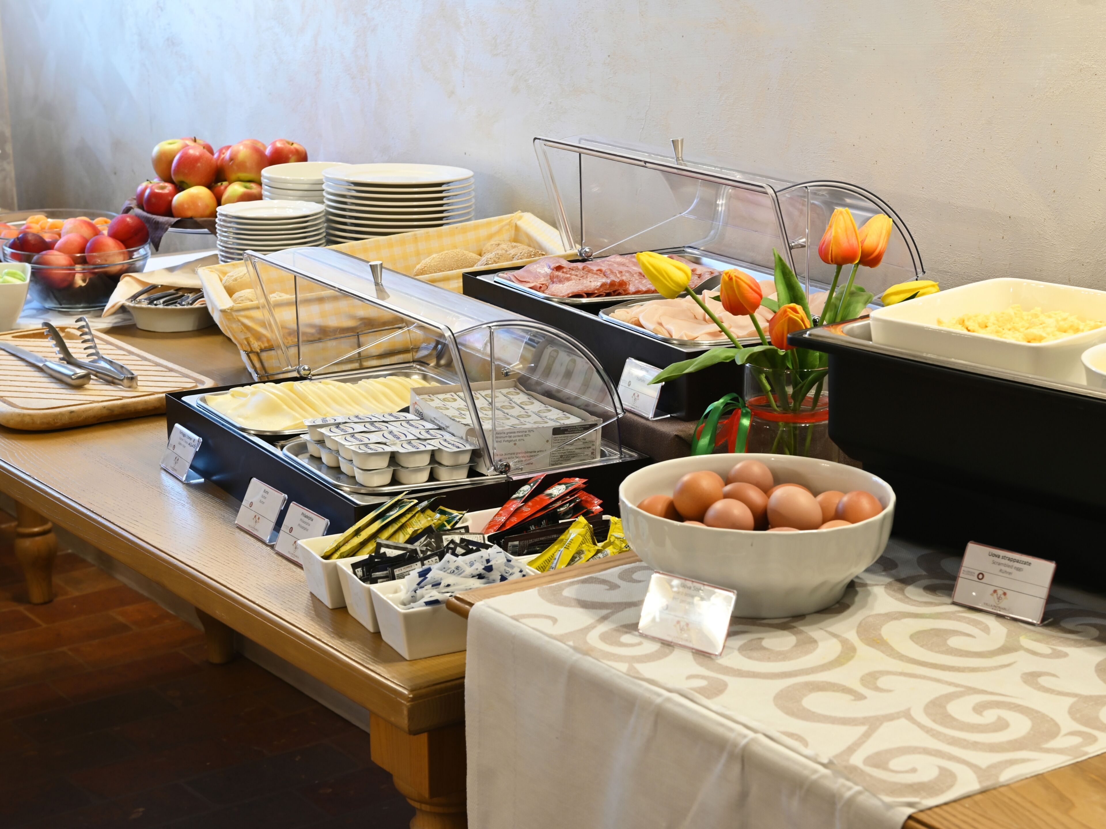Un bufé con diversos alimentos, como frutas, huevos y pasteles.