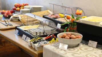 Un bufé con diversos alimentos, como frutas, huevos y pasteles.