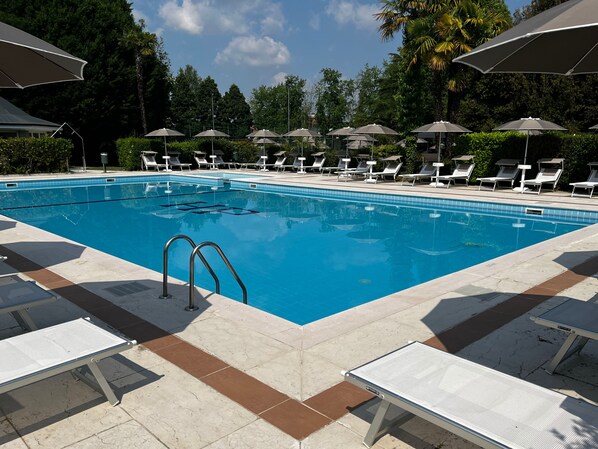 A swimming pool with lounge chairs and umbrellas. - Hotel Villa Patriarca - Buongiorno! Hotels (Mirano)