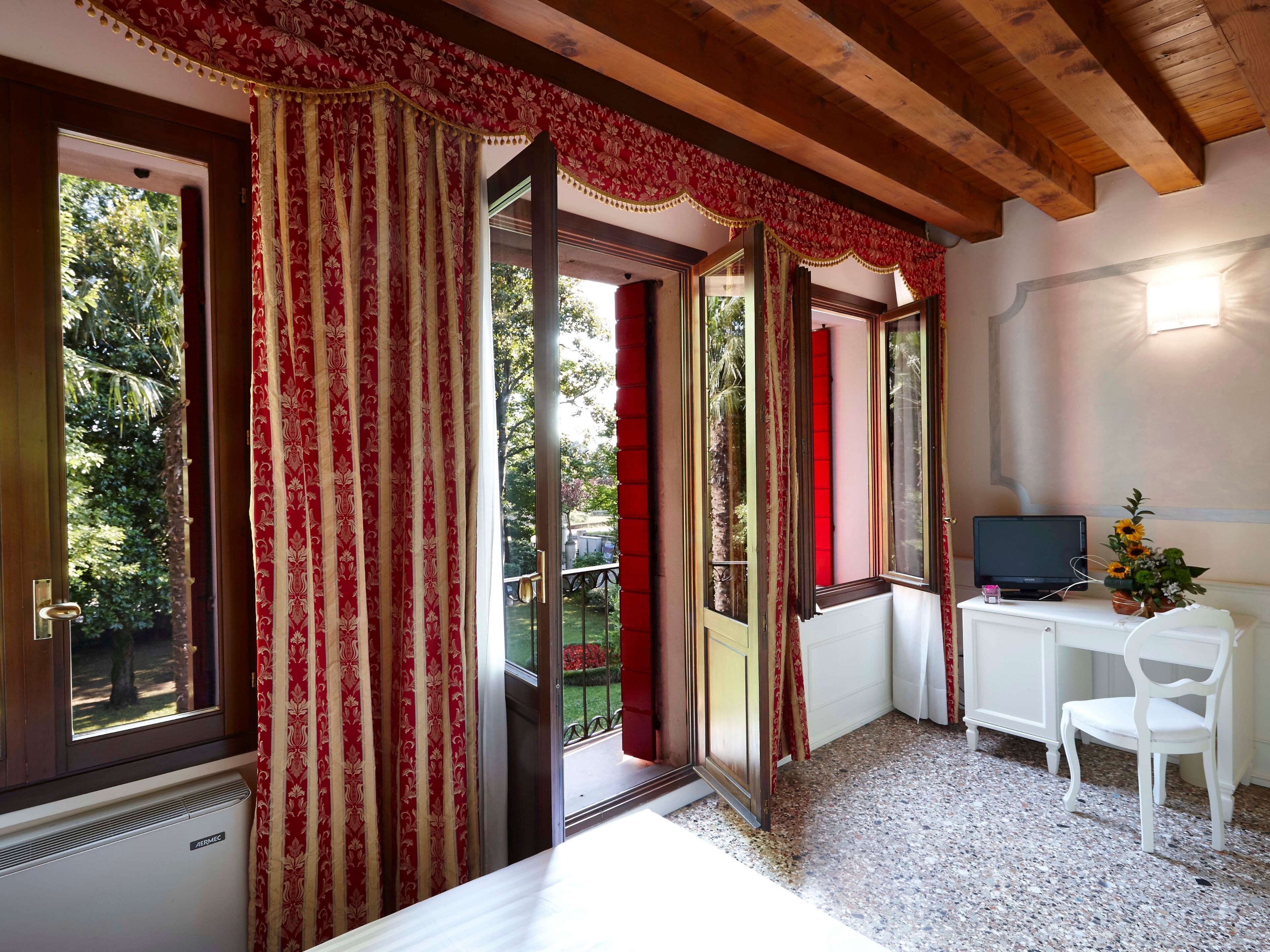 A room with a bed, a desk with a computer, a chair, and a window with curtains.