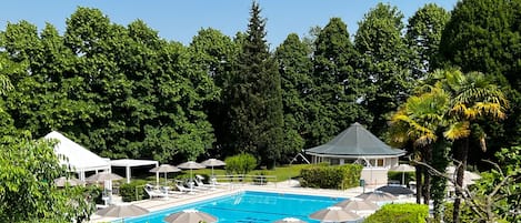 En säsongsöppen utomhuspool, parasoller och solstolar