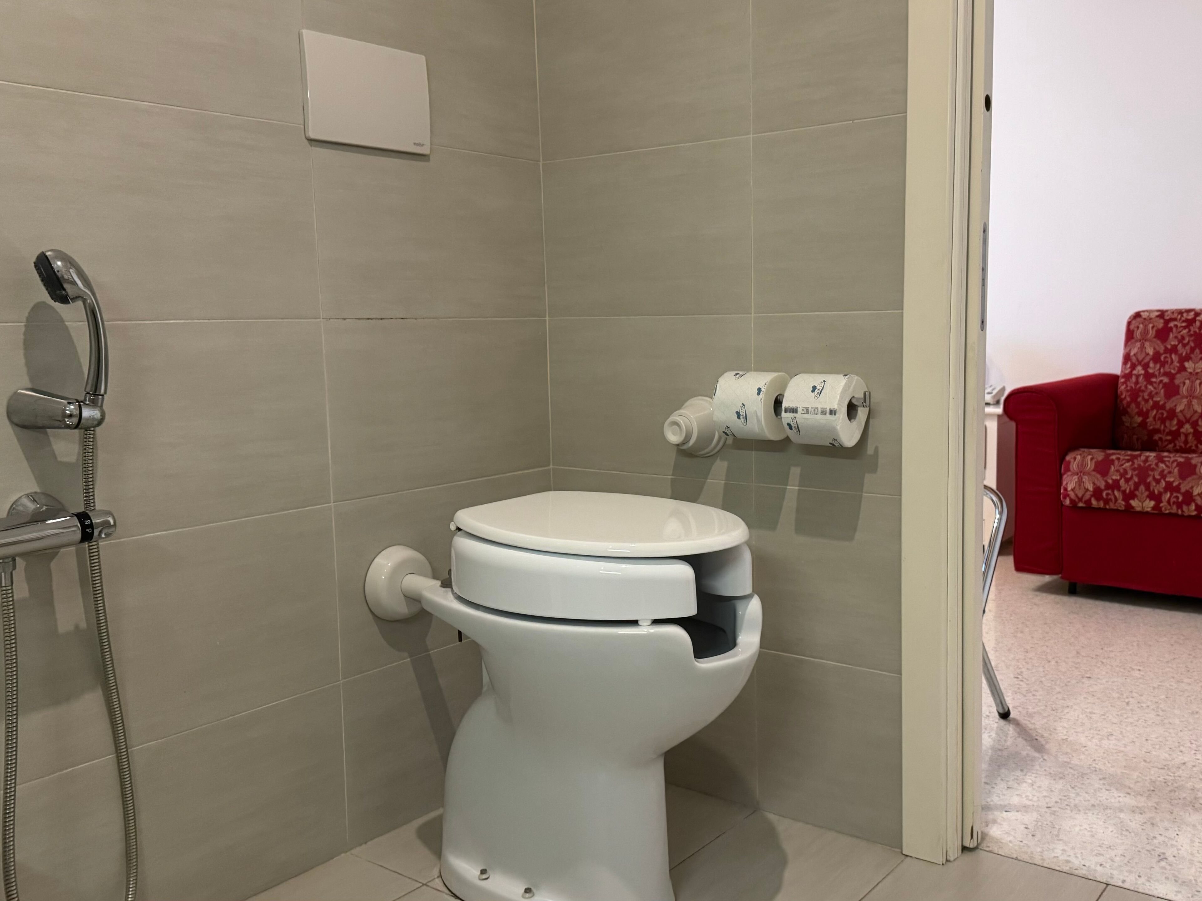 Une salle de bain moderne équipée de toilettes, d’une douche et d’un porte-rouleau de papier toilette.