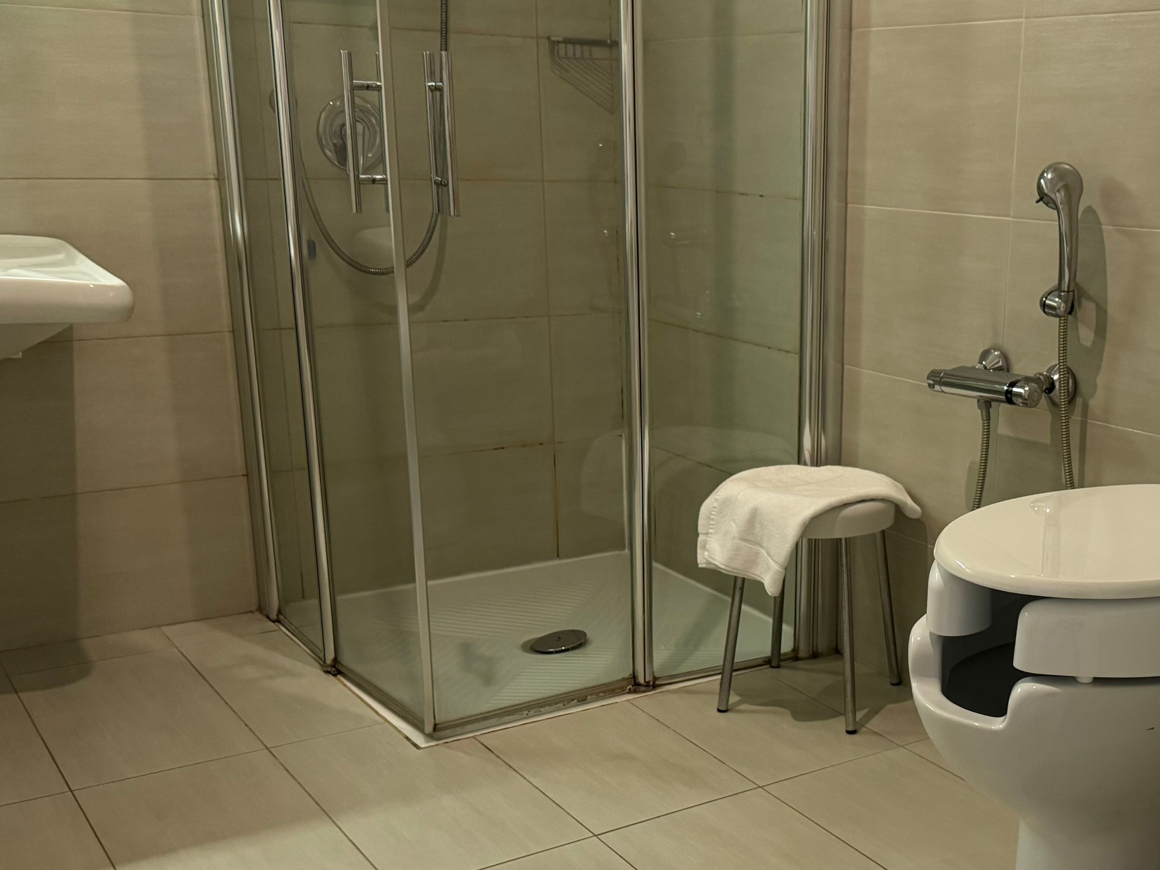 A modern bathroom with a glass-enclosed shower, a white sink, and a toilet.