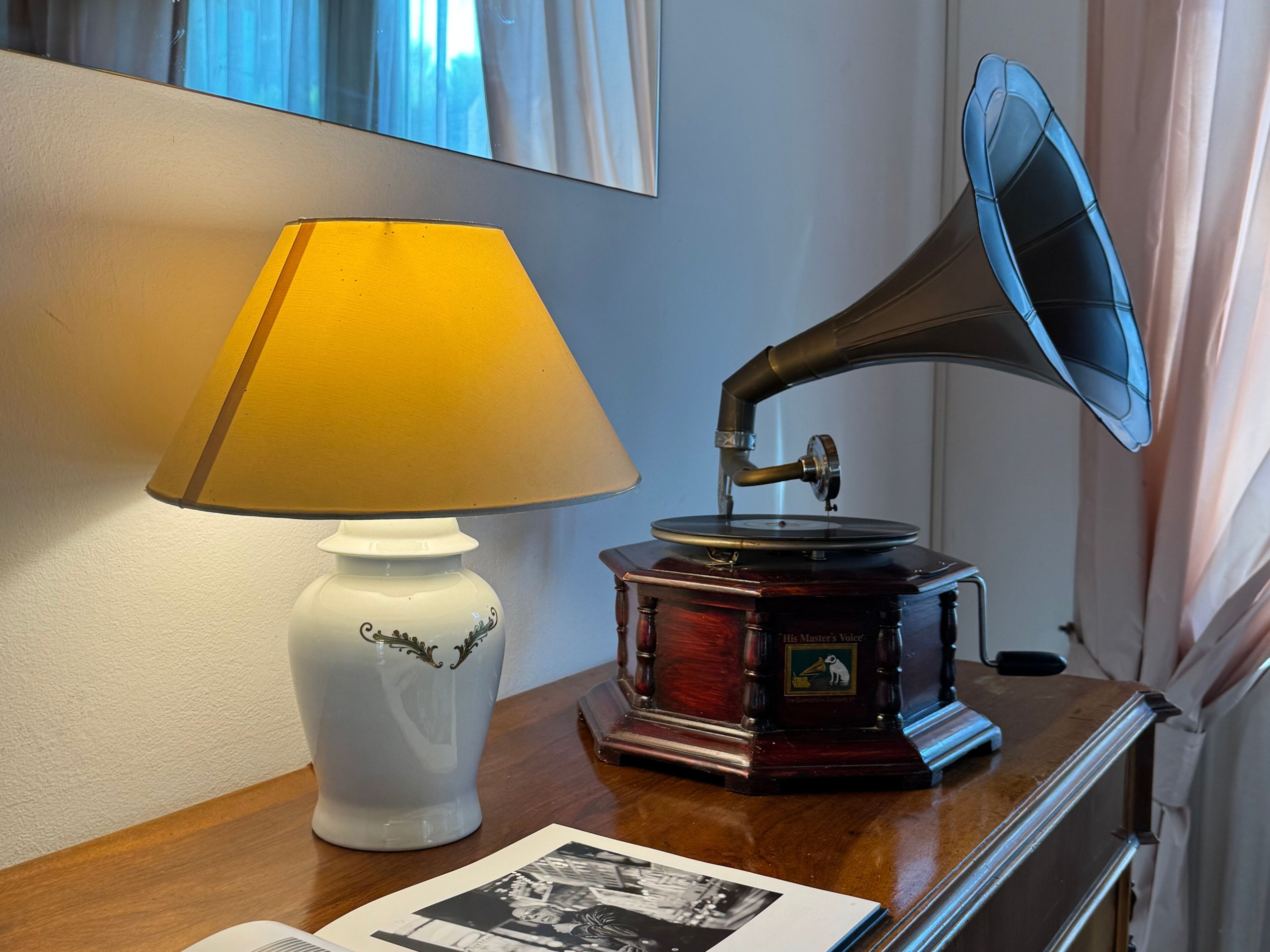 Una mesa con un tocadiscos antiguo, una lámpara blanca y una fotografía enmarcada.