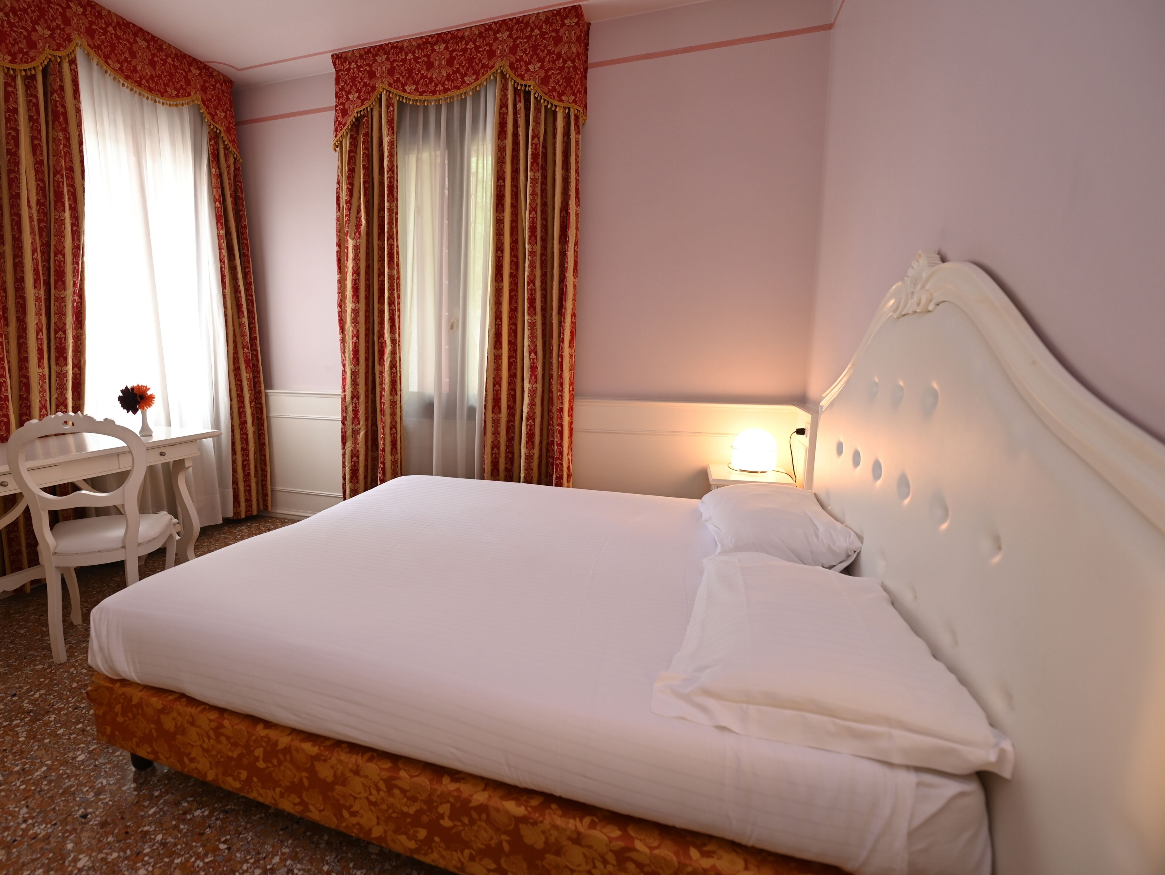 Een hotelkamer met een bed, een bureau en gordijnen.