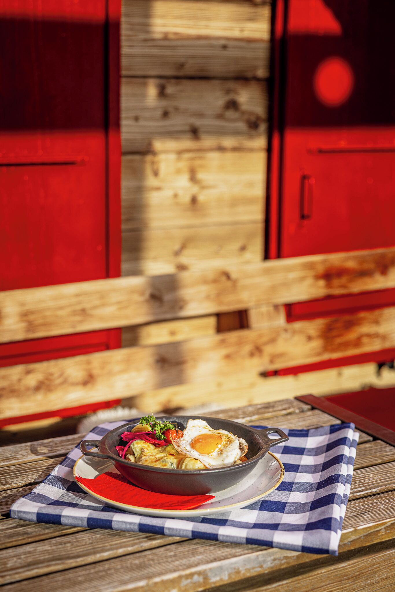 A breakfast dish on a checkered tablecloth with a wooden table and red cabinets in the background.
