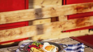 A breakfast dish on a checkered tablecloth with a wooden table and red cabinets in the background.