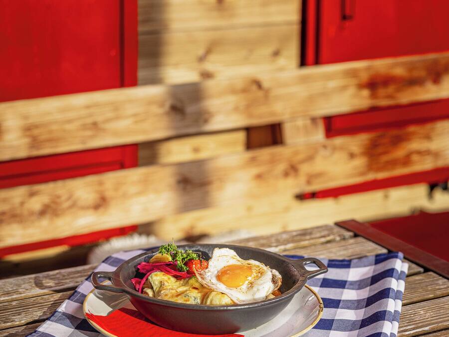 A breakfast dish on a checkered tablecloth with a wooden table and red cabinets in the background.