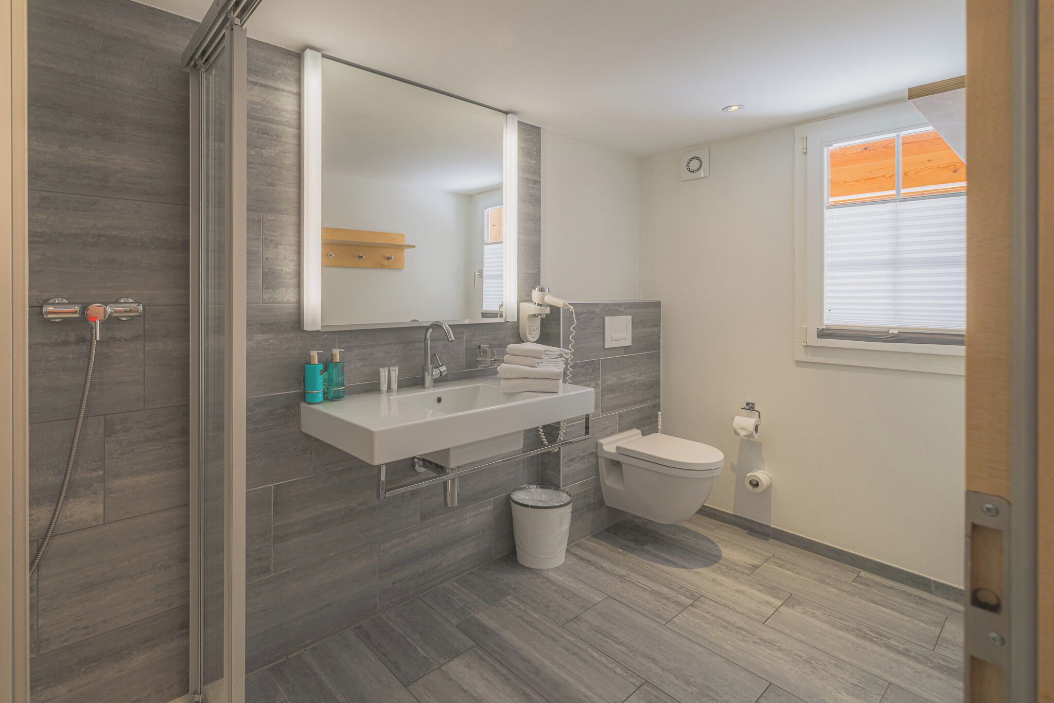 A modern bathroom with a shower, sink, and toilet.