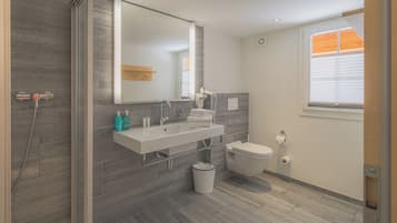 A modern bathroom with a shower, sink, and toilet.
