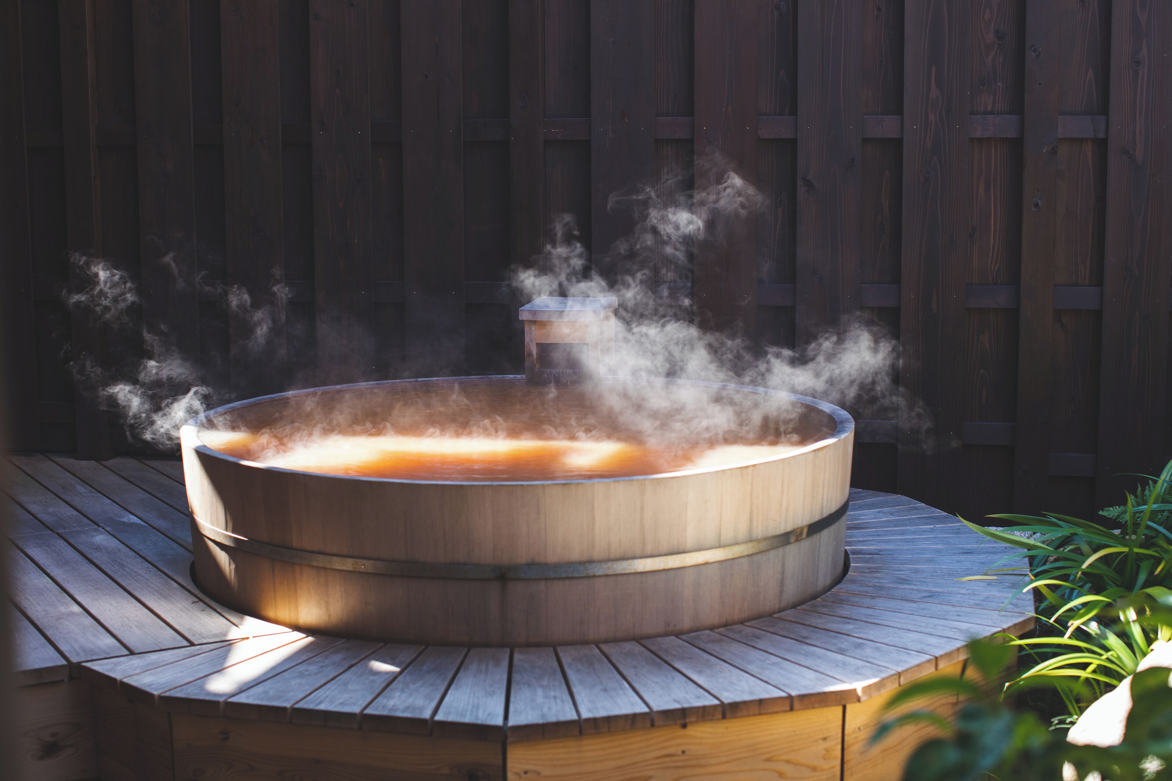 A hot tub in a wooden outdoor setting with steam rising.