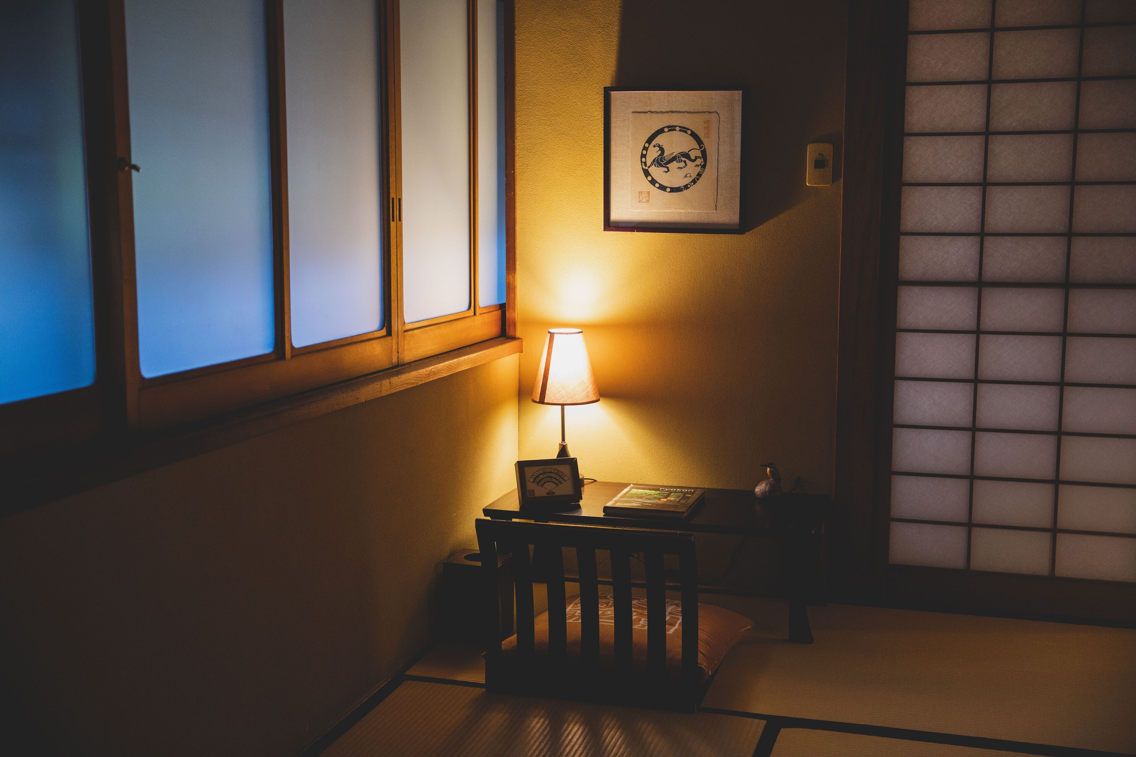 A traditional Japanese room with tatami flooring, a low table with a lamp, and a shoji screen.