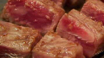 Close-up de carne cozida com centro rosado e exterior dourado.