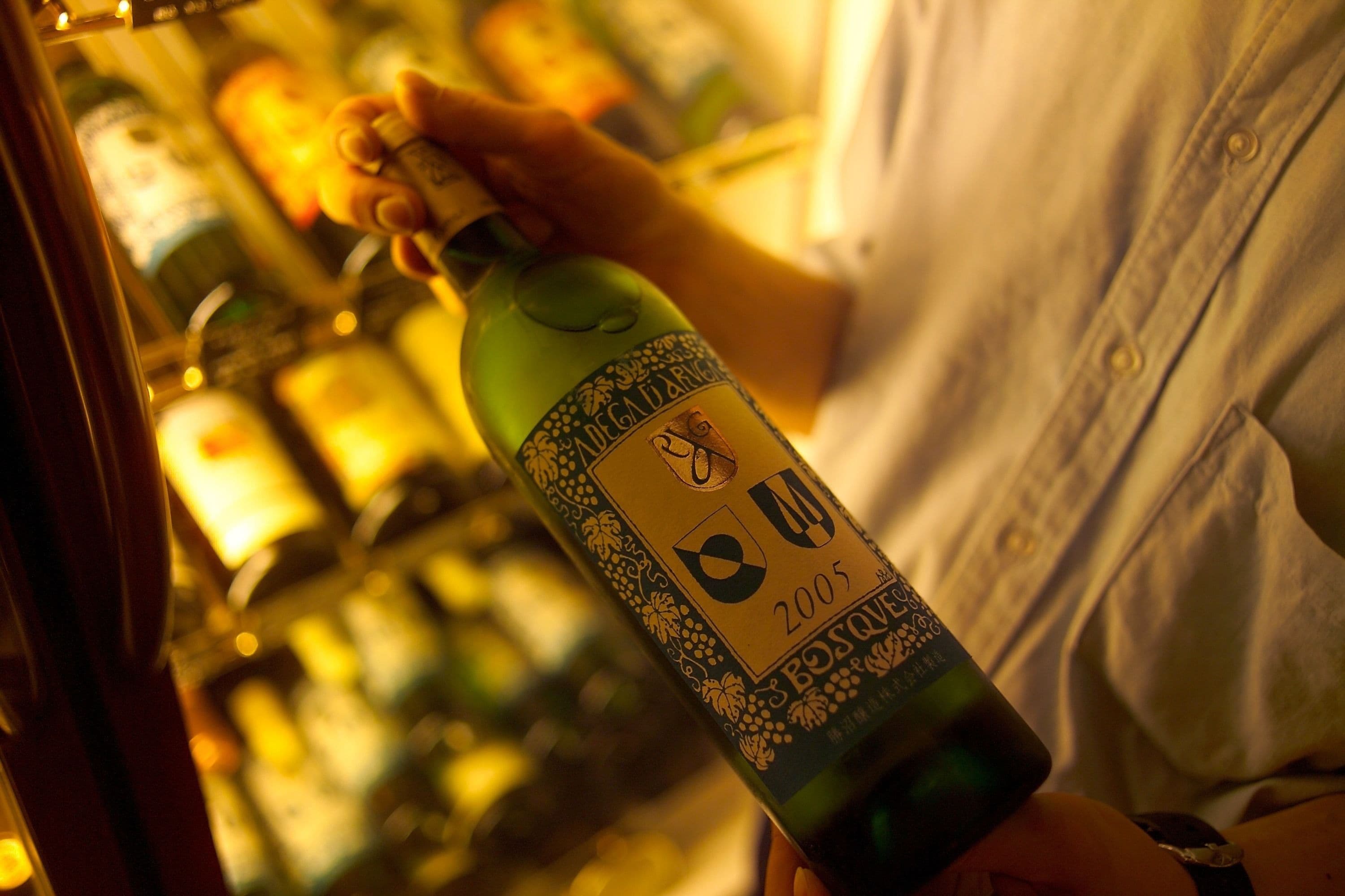 A person holding a bottle of wine with a label that includes the year 2005.