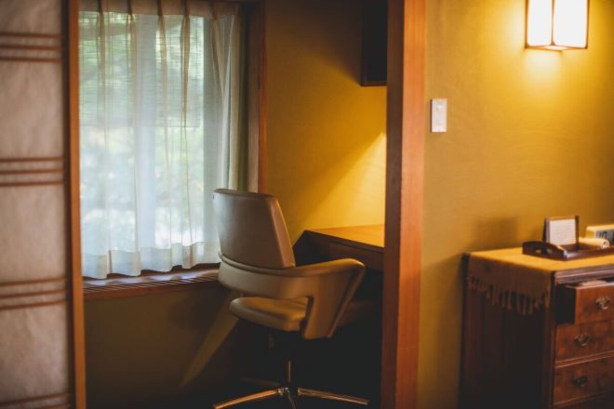 A room with a window, a chair, and a wooden dresser.