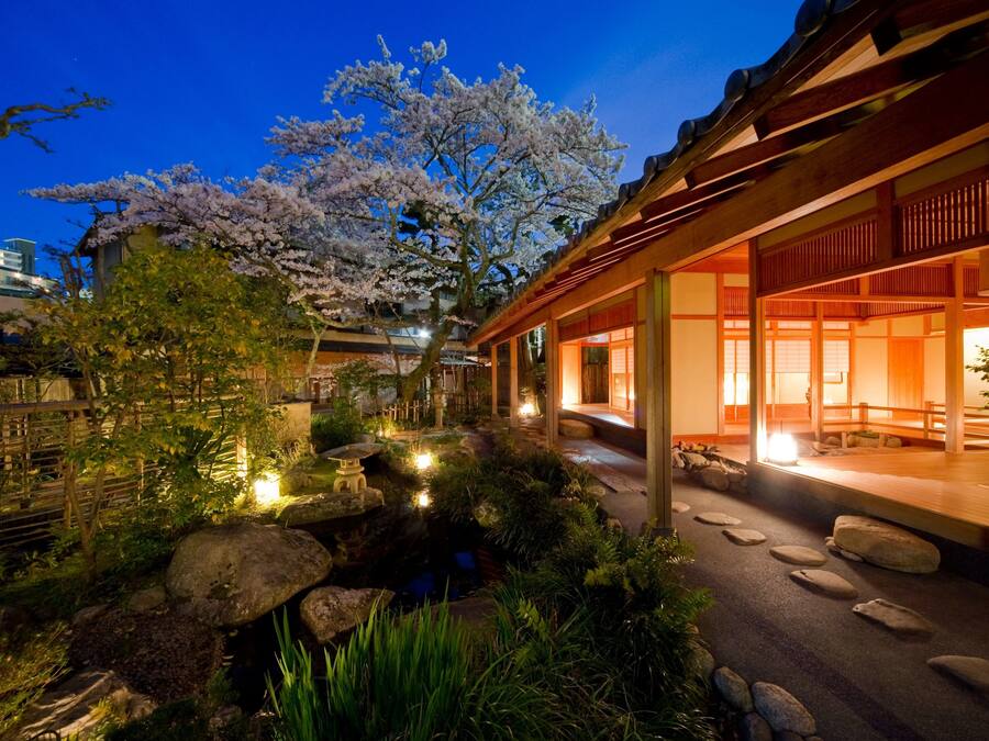 A traditional Japanese-style building with a garden, including a koi pond and cherry blossoms.