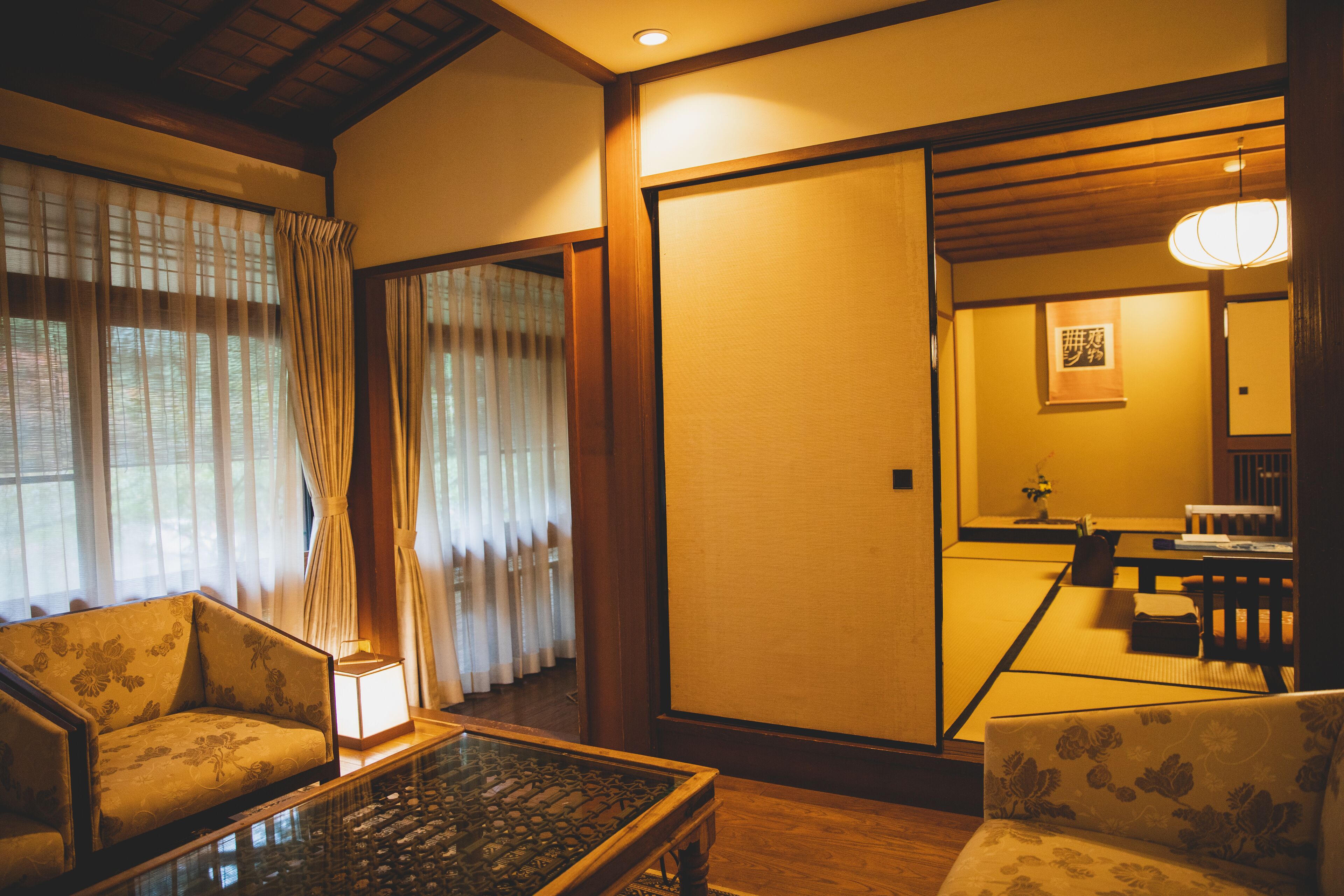 Una habitación japonesa tradicional con suelo de tatami, una mesa baja y dos futones de tatami con cojines.