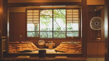 A traditional Japanese room with tatami flooring, a shoji screen window, and a circular wooden decoration.