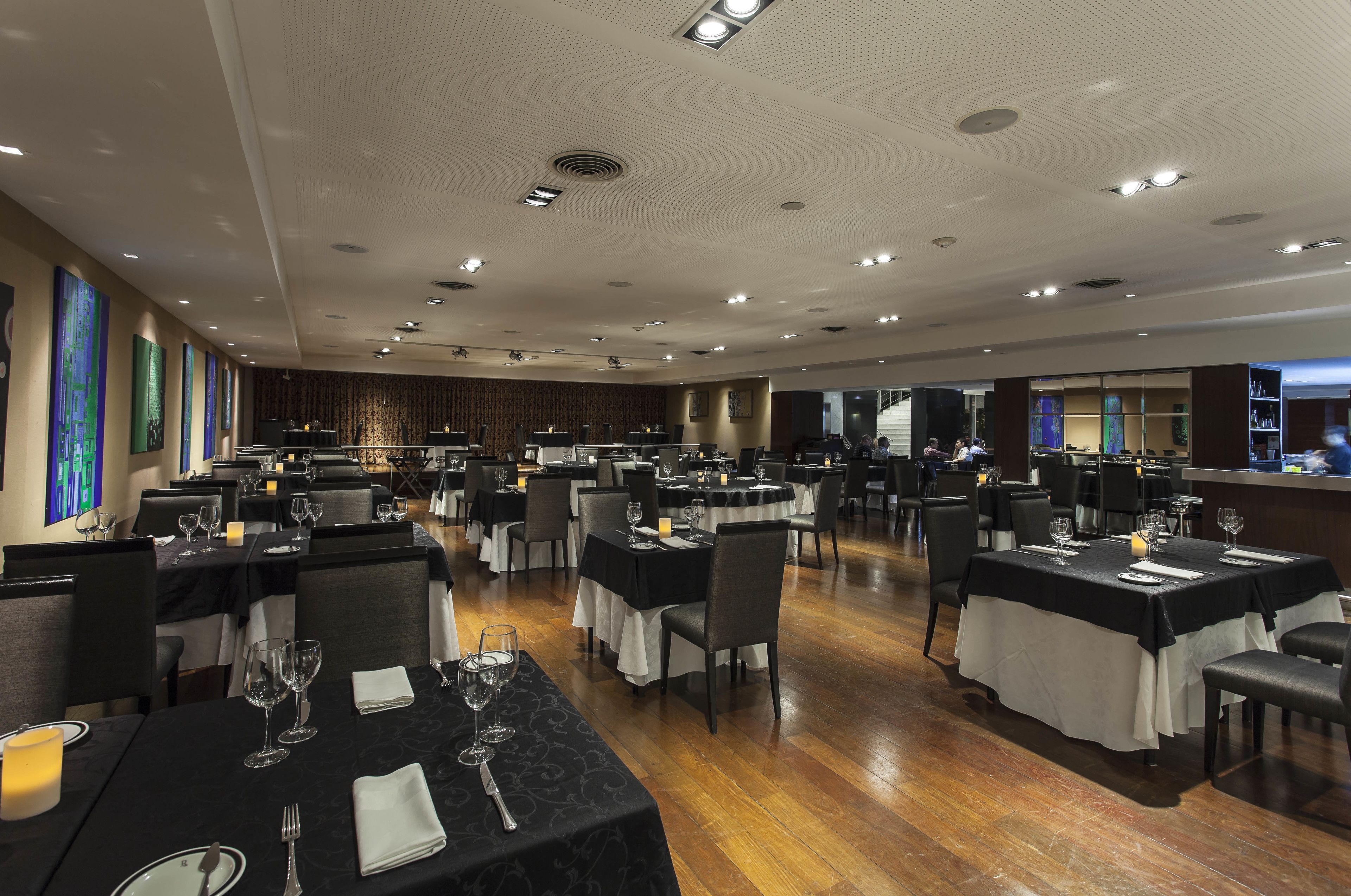 A spacious dining area with multiple tables, each set with wine glasses, plates, and cutlery.