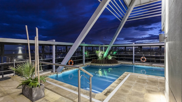 Una piscina en la azotea con vistas despejadas al perfil urbano al atardecer.