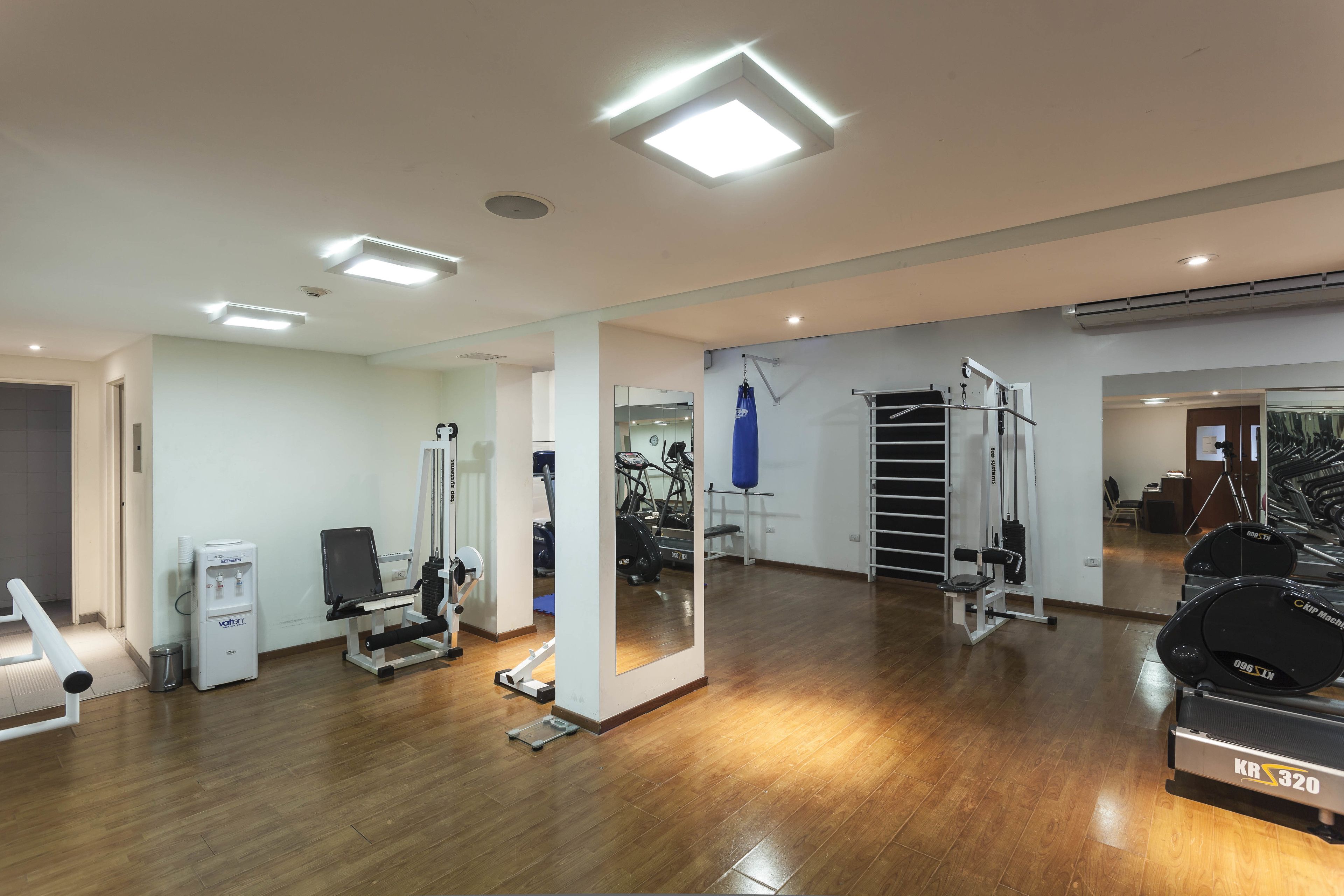 A spacious gym with various exercise equipment, including treadmills, a rowing machine, and a weight bench.