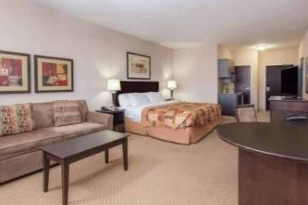 Habitación de hotel con cama, sofá, mesa de centro y escritorio.