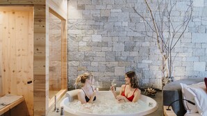 Two women in a spa-like setting with a stone wall and wooden elements. - Hotel Lac Salin Spa & Mountain Resort (Livigno)