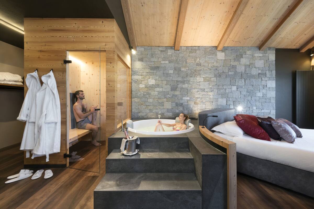 Un moderno cuarto de spa con pared de piedra, techo de madera y una cama con almohadones.