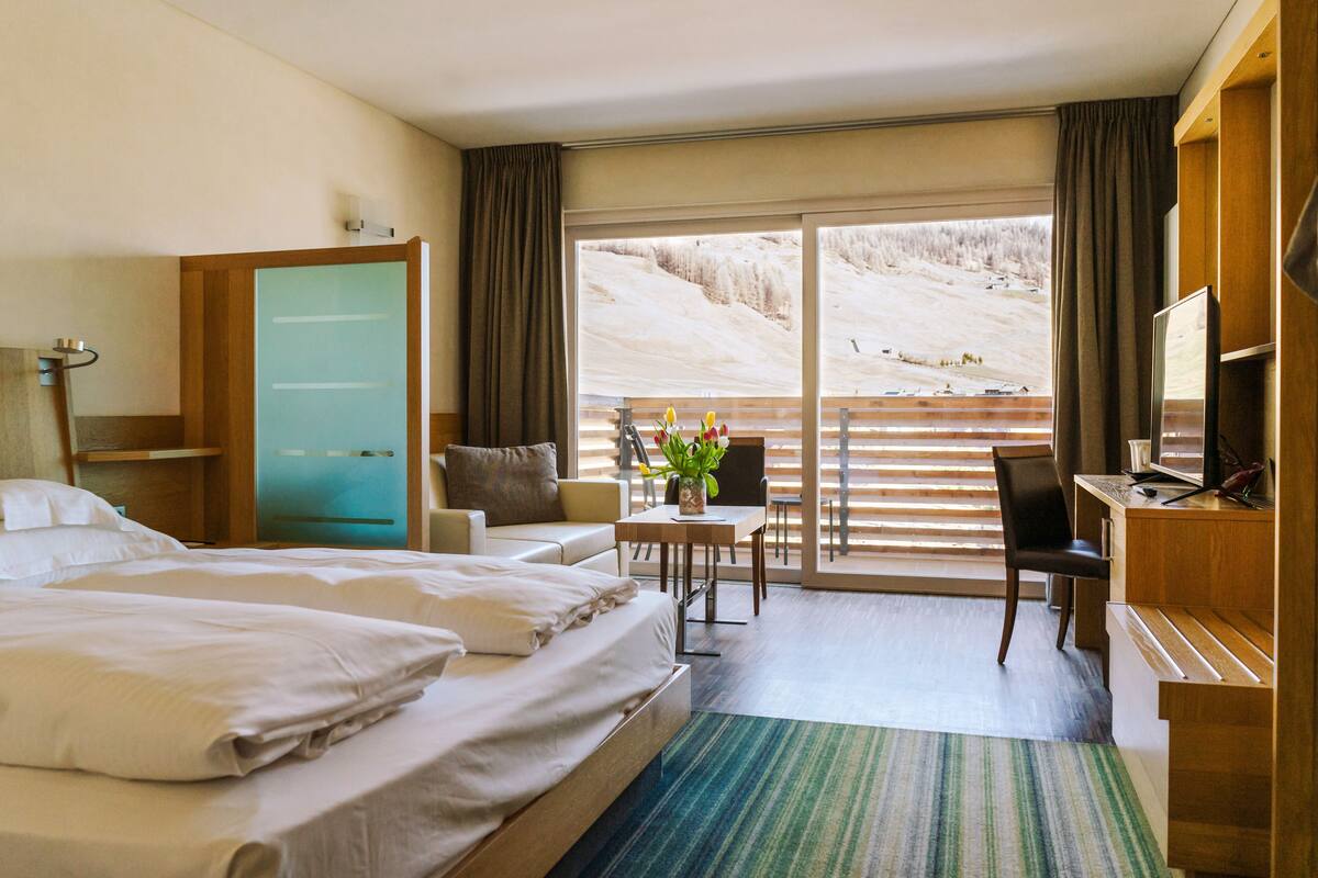 Habitación de hotel con cama, escritorio, silla y vistas a un paisaje nevado.