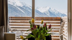 A balcony with a wooden railing, a table with a vase of flowers, and a view of snow-capped mountains. - Hotel Lac Salin Spa & Mountain Resort (Livigno)