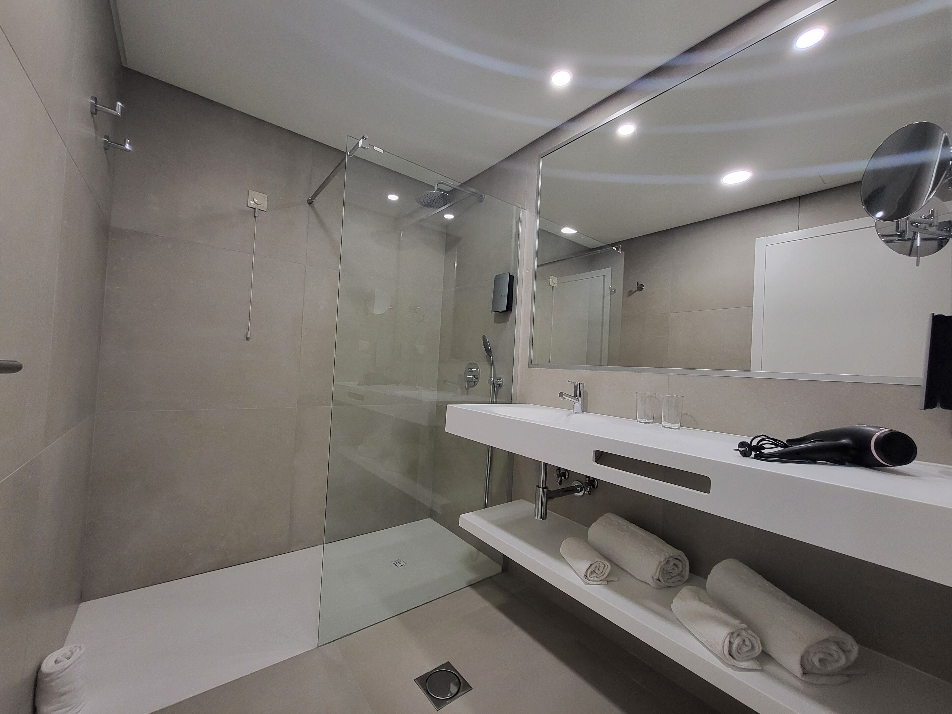 A modern bathroom with a glass-enclosed shower, a white sink, and a mirror.