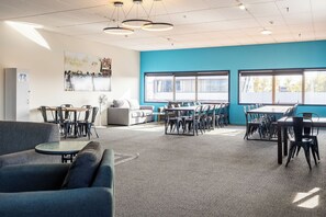 A modern conference room with multiple tables and chairs, large windows, and a blue accent wall. - Rock Solid Backpackers Rotorua (Rotorua)