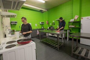 Une cuisine aux murs verts, dotée d’appareils électroménagers en acier inoxydable et d’un réfrigérateur blanc.