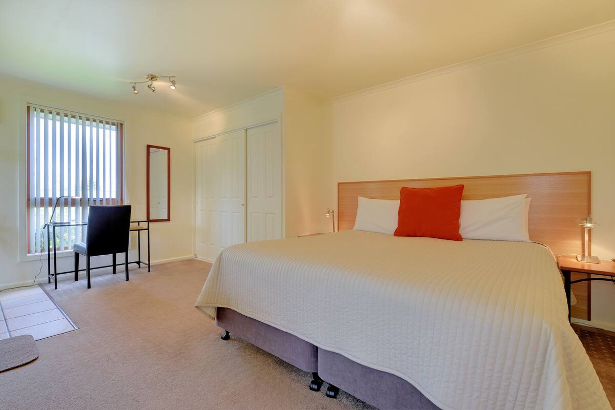 A bedroom with a large bed, a desk, and a chair.