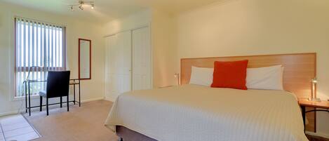 A bedroom with a large bed, a desk, and a chair.