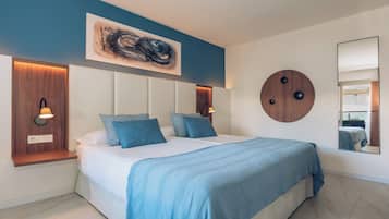 Un dormitorio moderno con una cama grande, una pared azul de acento, un detalle redondo de madera y un cuadro abstracto de gran tamaño.